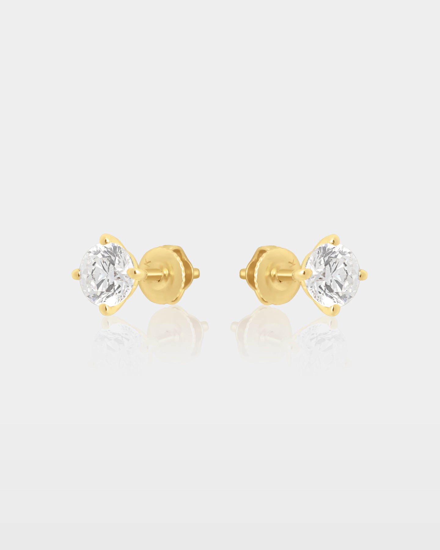 Side and rear studio view of 1.01ct round diamond solitaire four-prong stud earrings showing the 14k yellow gold posts and metal backs