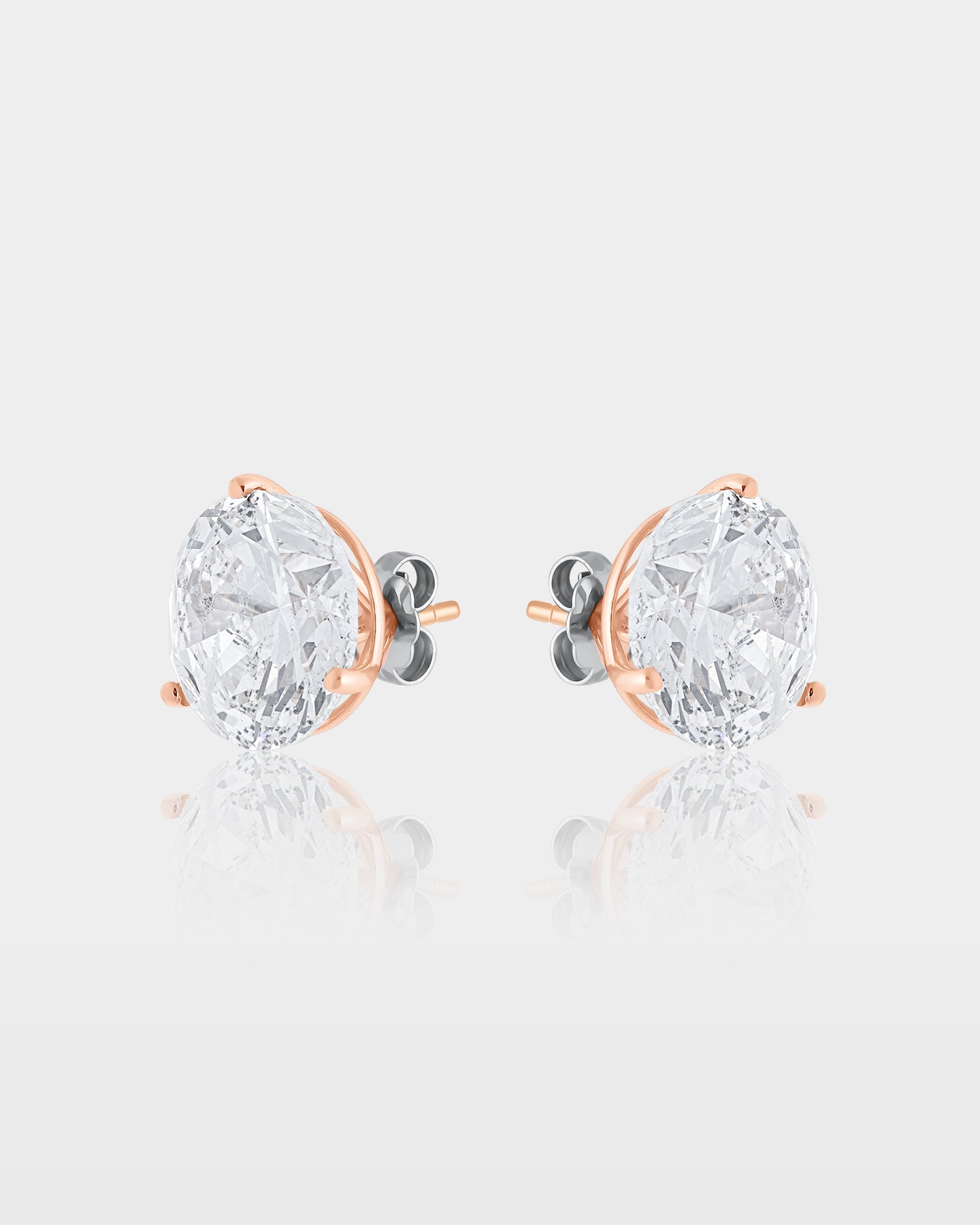 Side and rear studio view of substantial 10ct round diamond solitaire three-prong stud earrings showing the 14k rose gold posts and heavy-duty backs