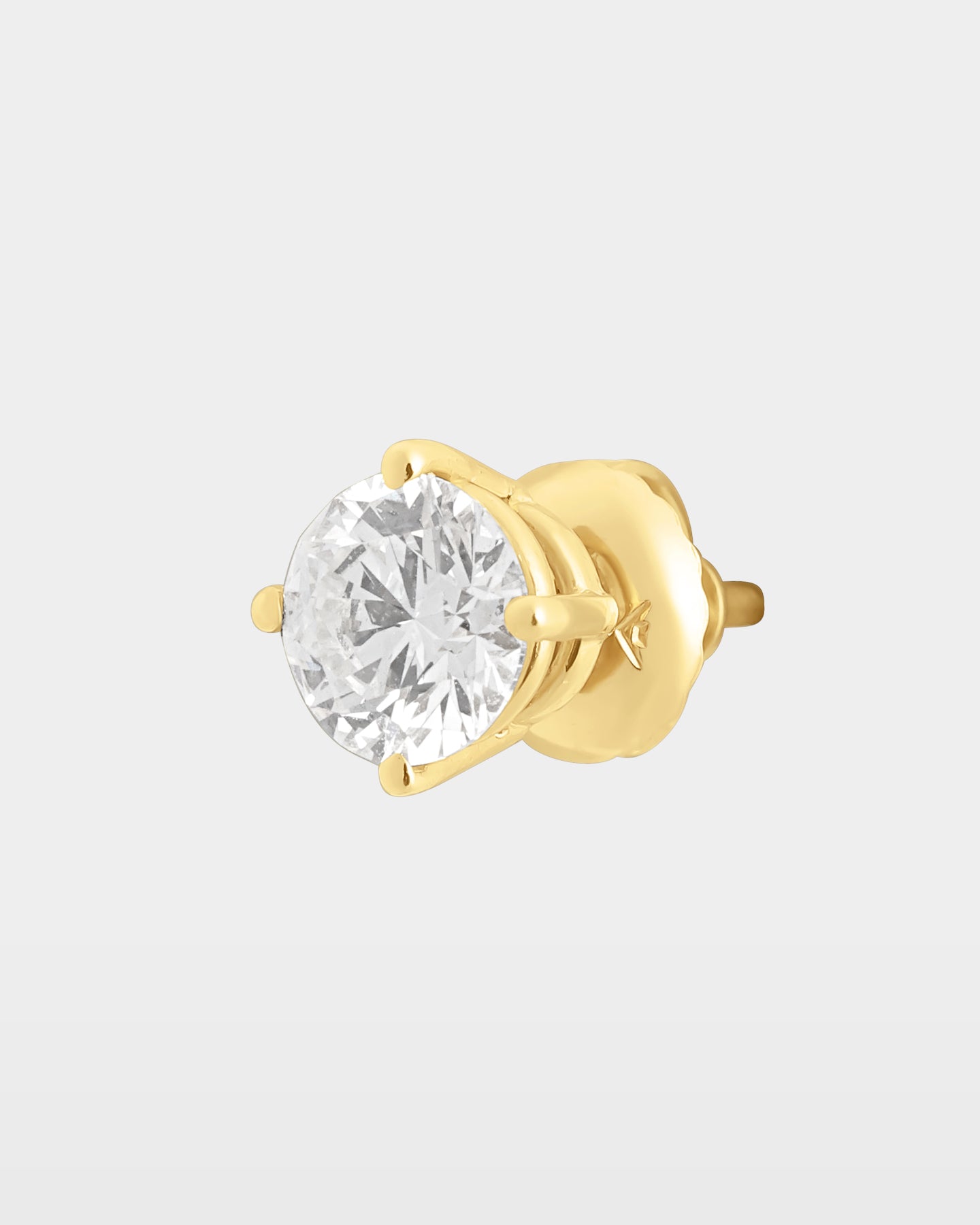 ngled studio macro shot of a single round diamond solitaire stud earring in a 10k yellow gold four-prong basket