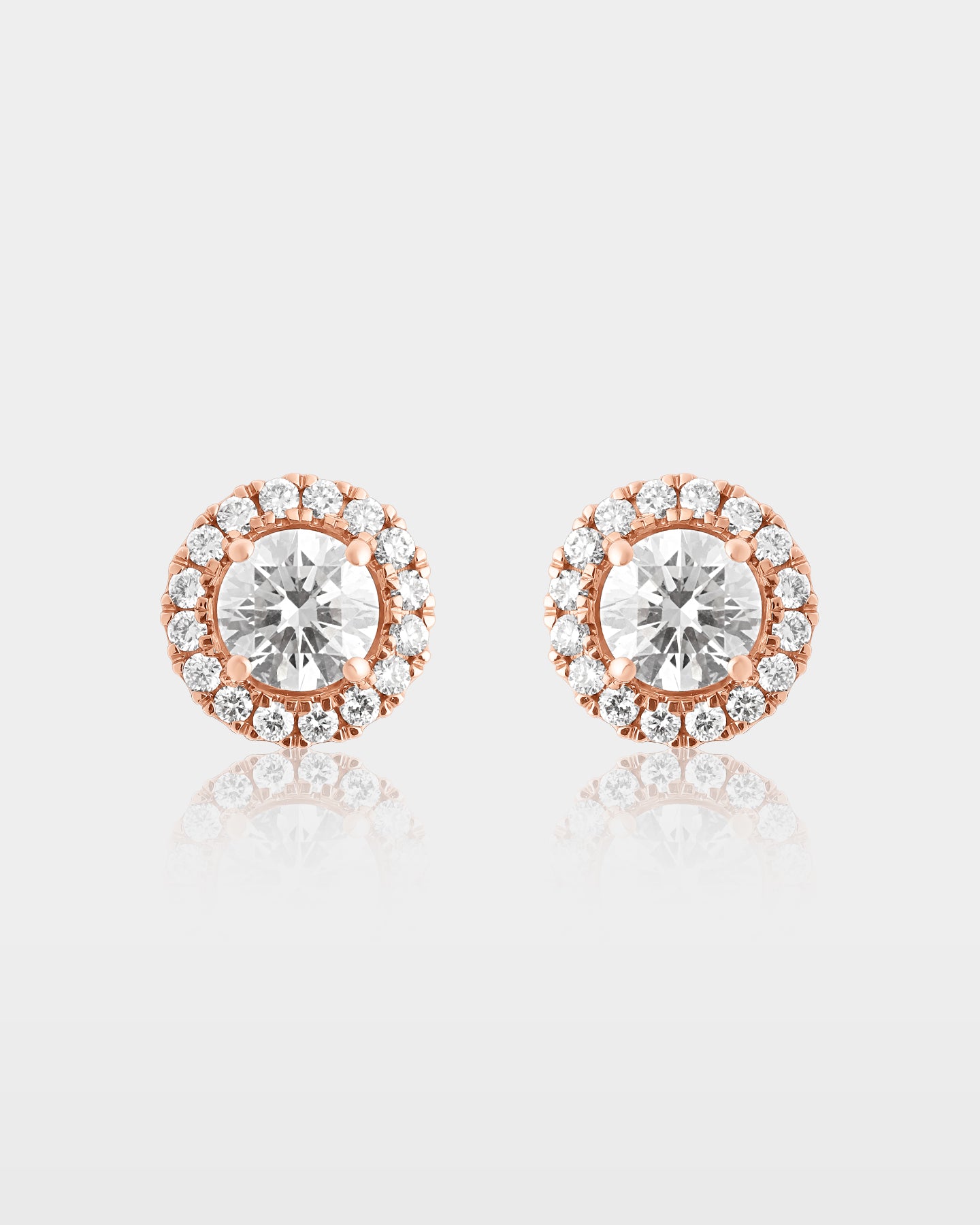 A pair of round brilliant-cut diamond stud earrings featuring a delicate micro pave diamond halo frame in 10k rose gold