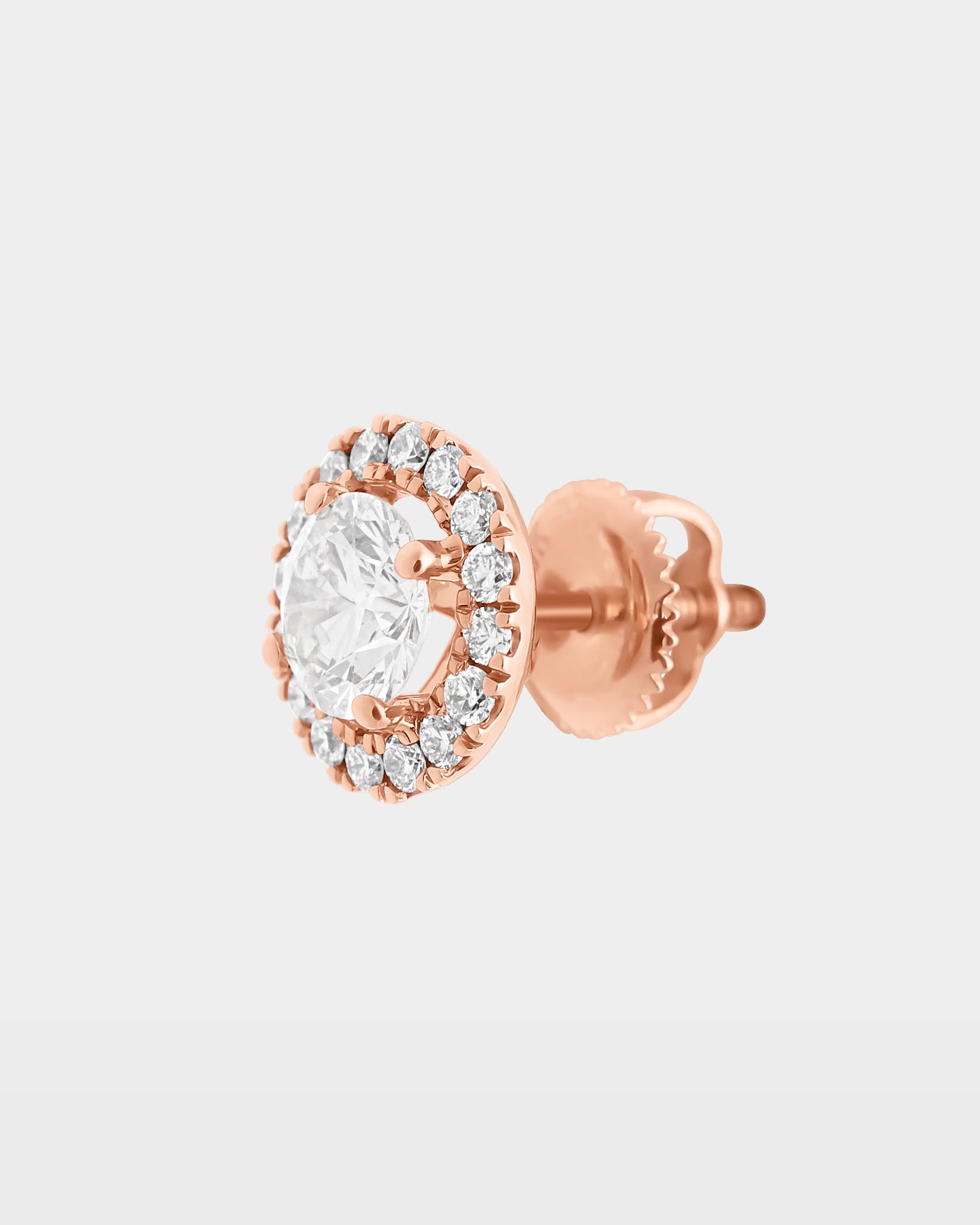 An angled studio macro shot of a single circular round diamond halo pavé stud earring showcasing the raised center setting and rose gold basket