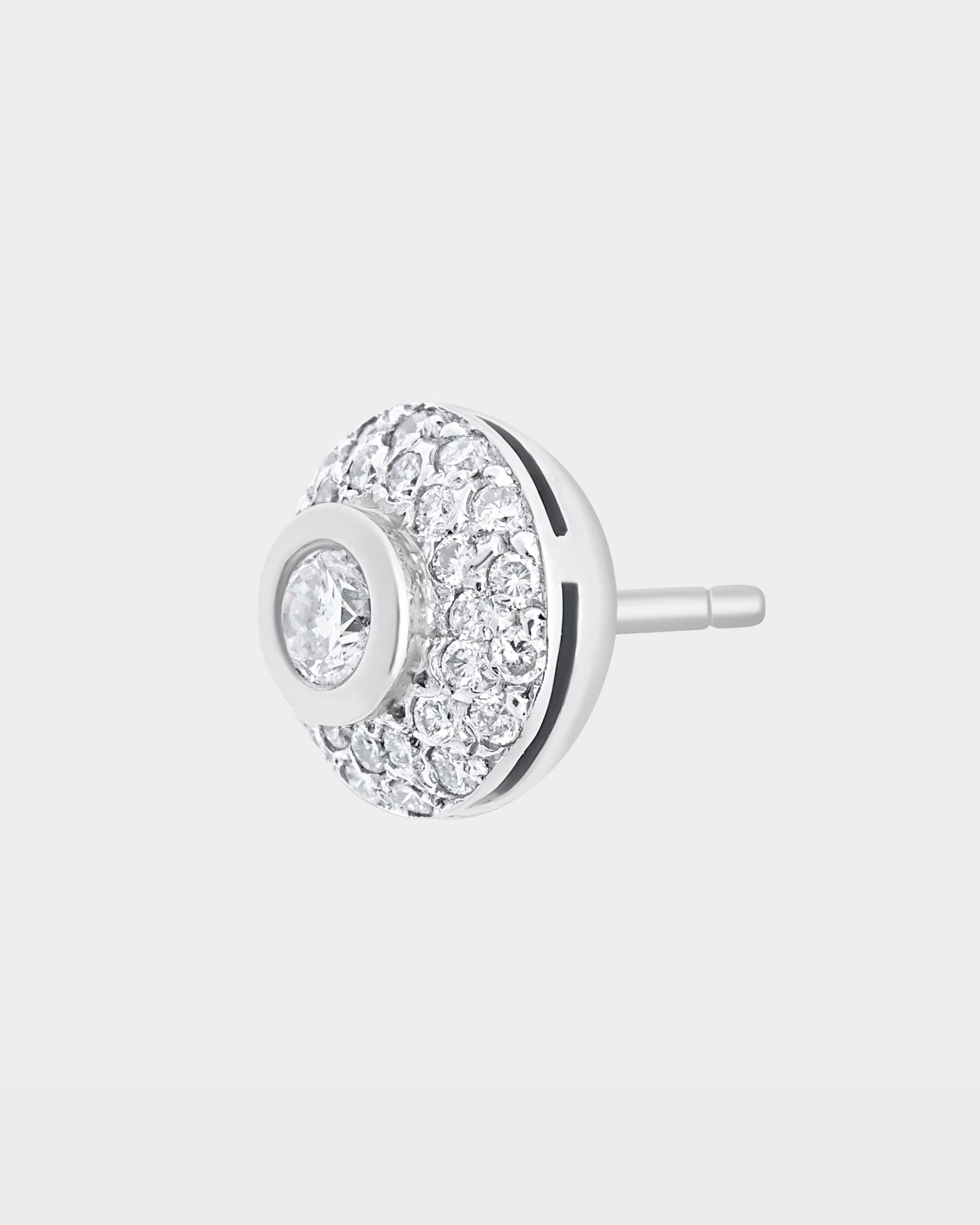An angled studio macro shot of a single circular dome pave diamond stud earring showcasing the raised center bezel setting