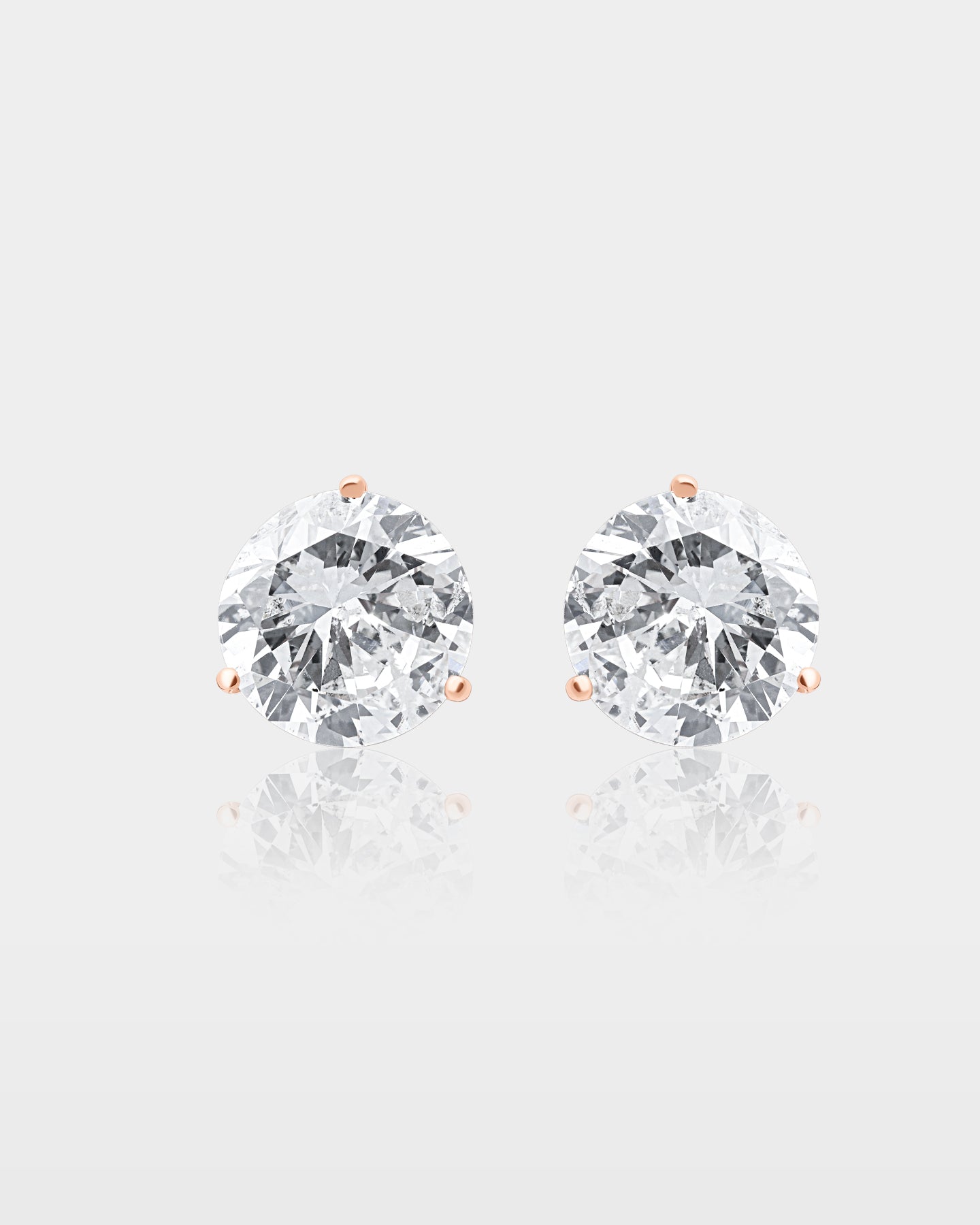 A pair of massive 10 carat total weight round brilliant-cut diamond solitaire stud earrings set in minimalist 14k rose gold three-prong settings