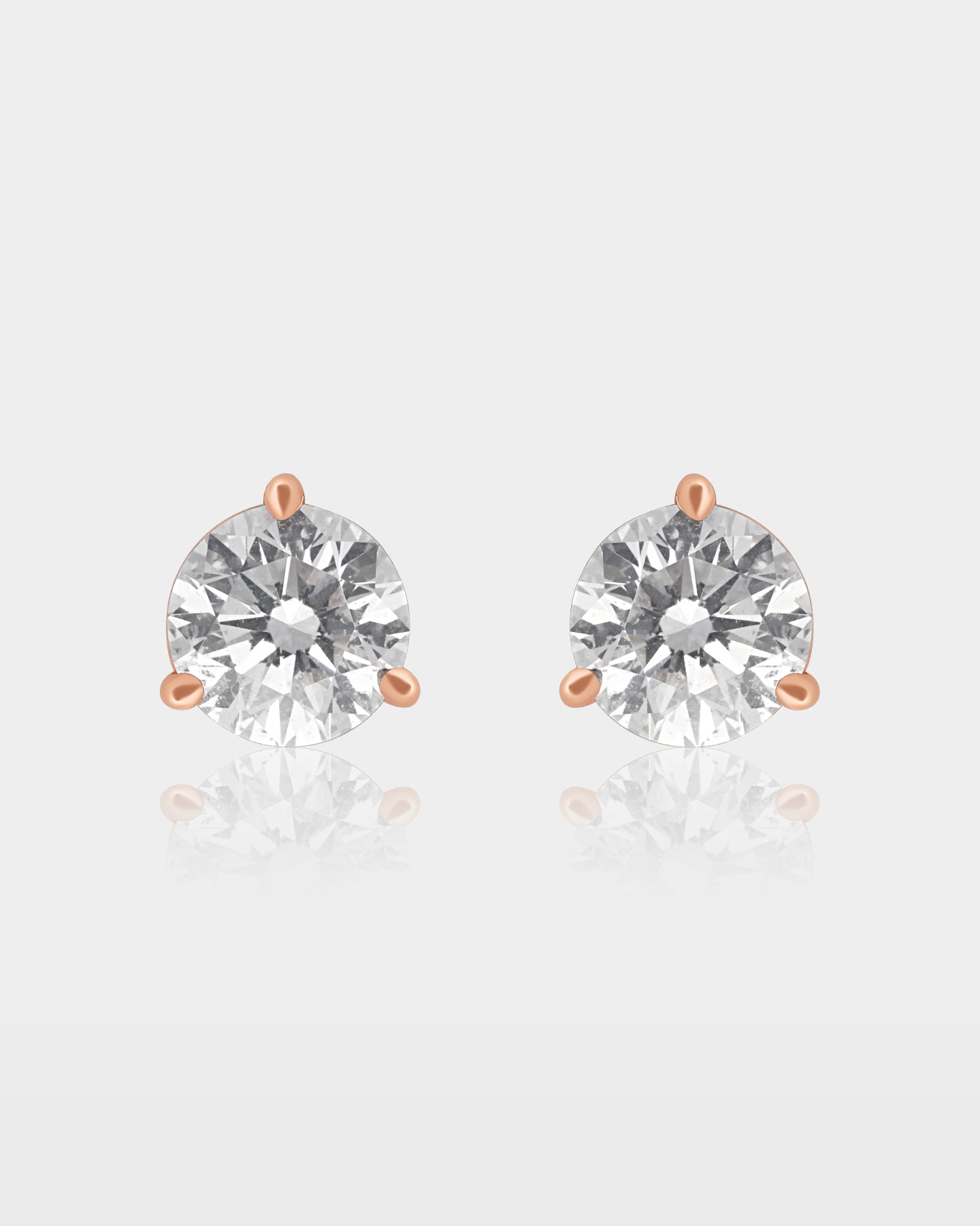 air of round brilliant-cut diamond solitaire stud earrings in a 14k rose gold three-prong martini setting