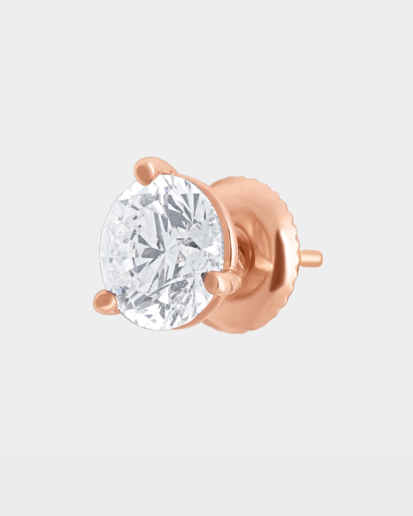angled studio macro shot of a single round diamond solitaire stud earring in a 14k rose gold 3-prong martini basket