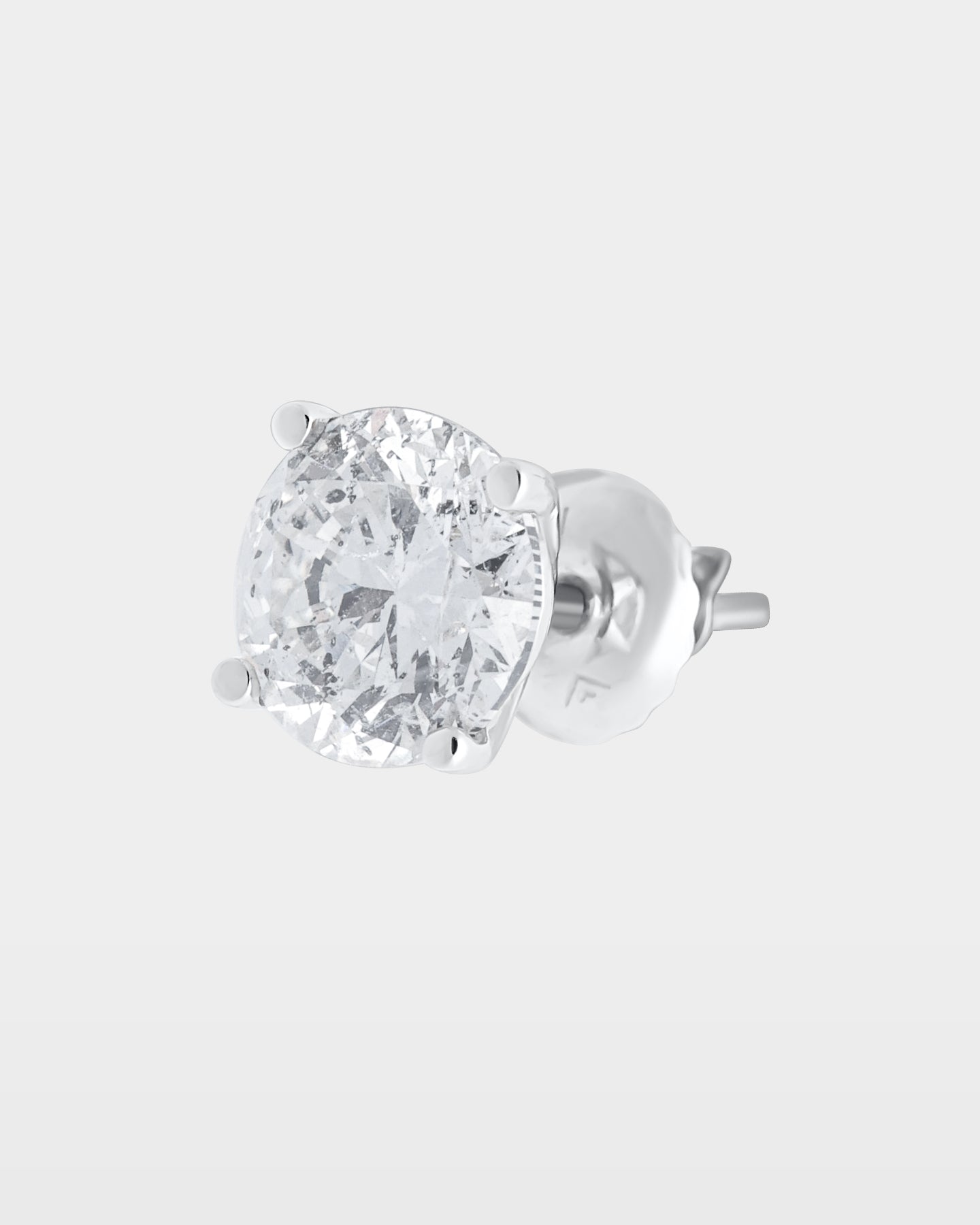 An angled studio macro shot of a single round brilliant diamond solitaire stud earring in a 14k white gold 4-prong basket setting