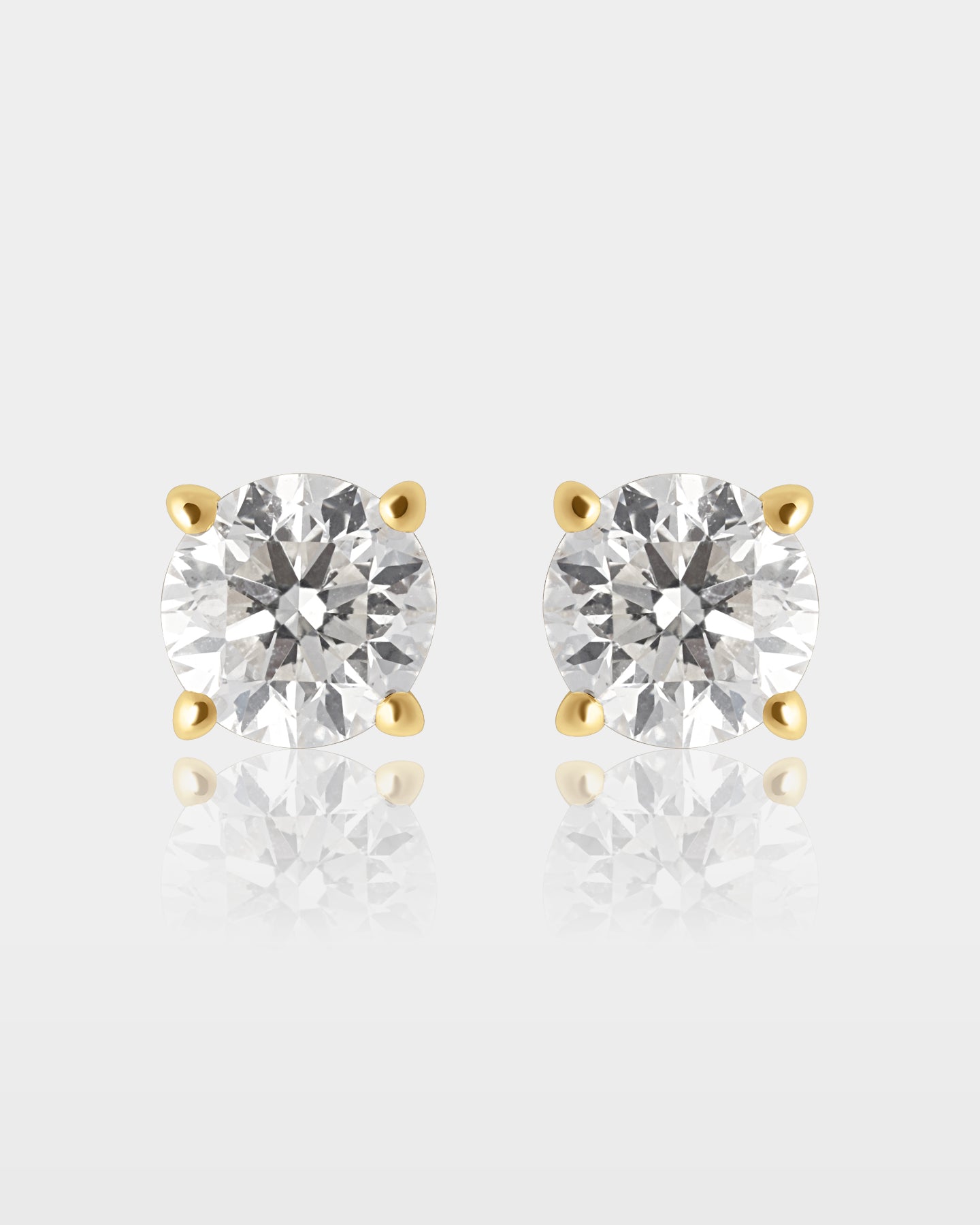 A pair of 1.01 carat total weight round brilliant-cut diamond solitaire stud earrings set in traditional 14k yellow gold four-prong basket settings