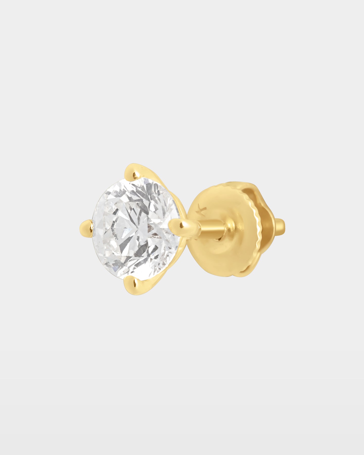 An angled studio macro shot of a single 1.01ct round brilliant diamond solitaire stud earring in a 14k yellow gold 4-prong setting