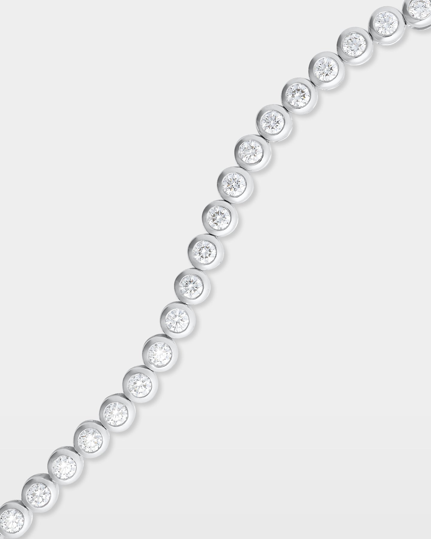 A close-up studio shot showing the curved articulation and detailed metalwork of a white gold bezel diamond tennis bracelet