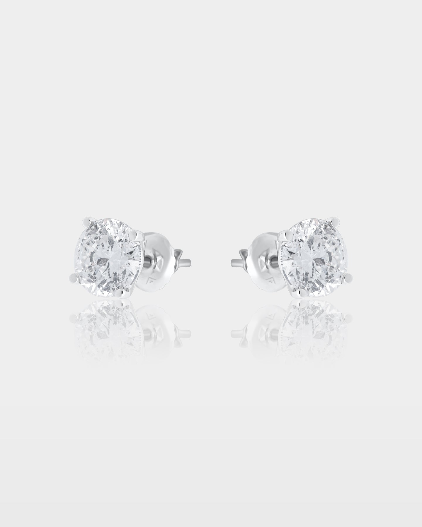 Side and rear studio view of classic round diamond solitaire four-prong stud earrings showing the white gold posts and metal friction backs