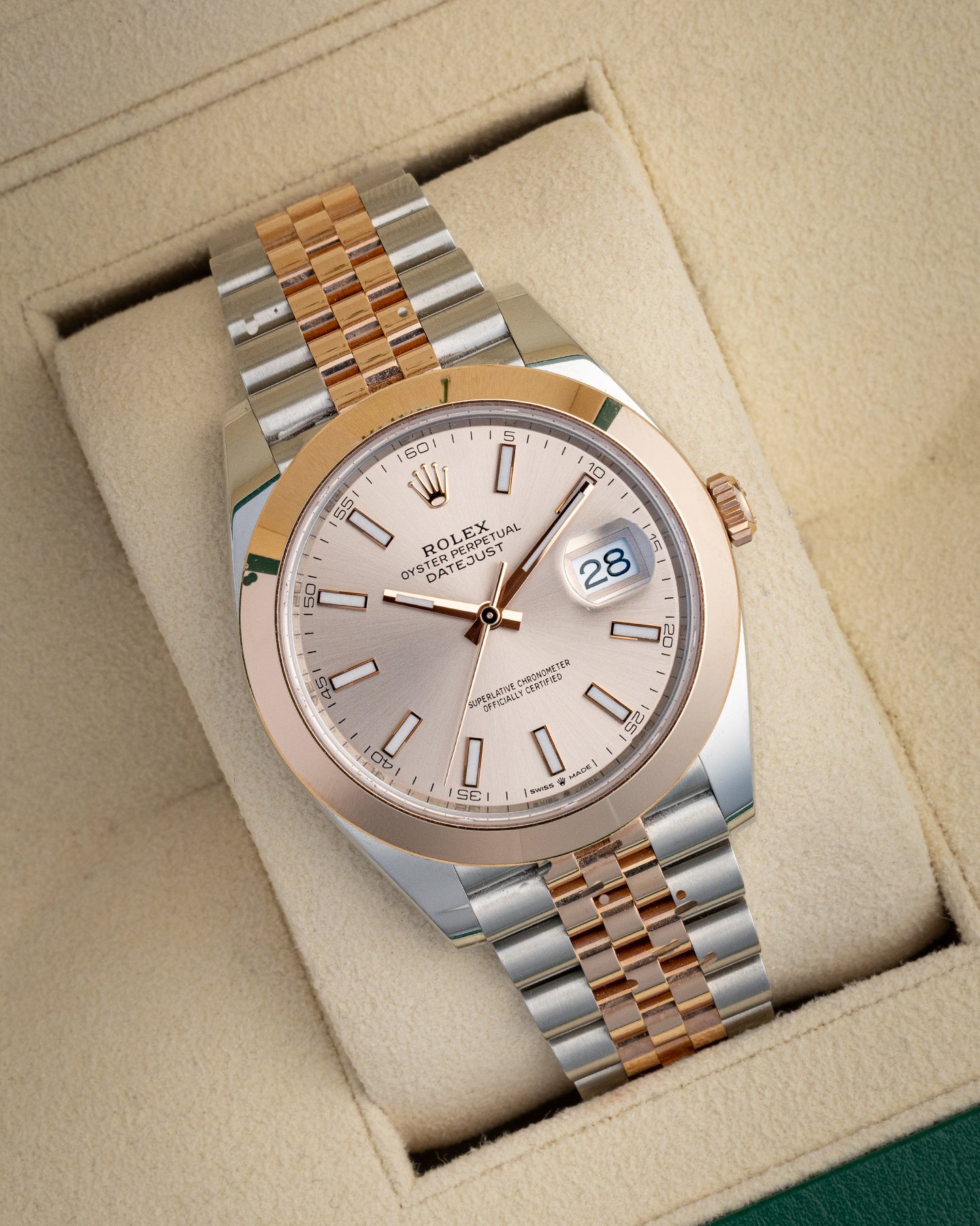 angled studio view of a 41mm Everose Rolesor Rolex Datejust with a metallic Sundust dial resting on a cream watch presentation pillow
