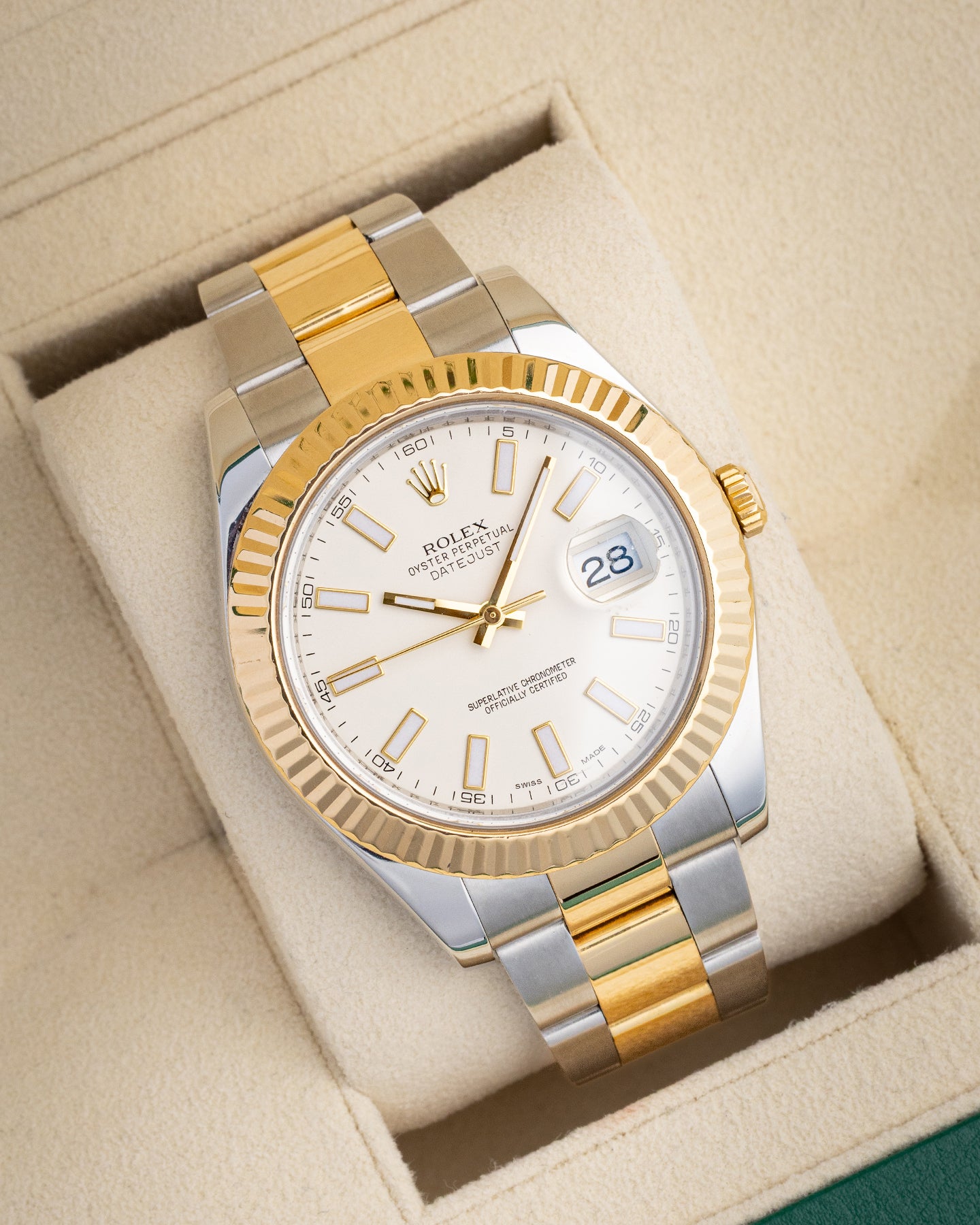 angled close-up view of a two-tone yellow gold and steel Rolex Datejust II reference 116333 resting on a cream watch pillow