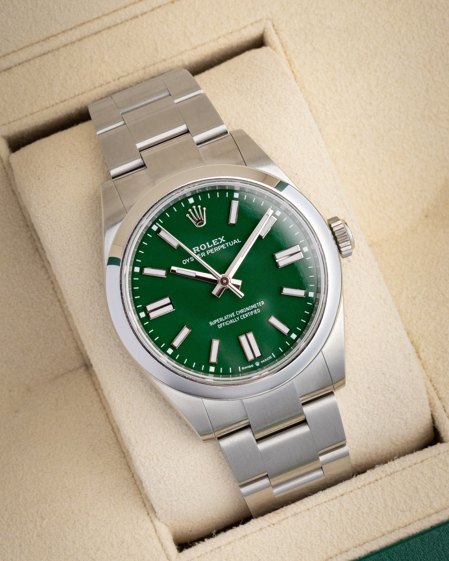 angled view of a 41mm Rolex Oyster Perpetual with a green lacquer dial resting securely on a cream leather watch pillow