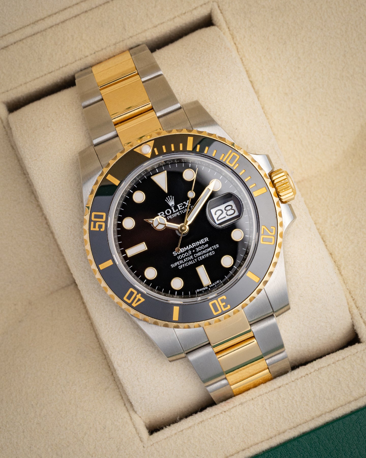 angled view of a 40mm two-tone Rolex Submariner Date with a black dial resting on a cream watch presentation pillow