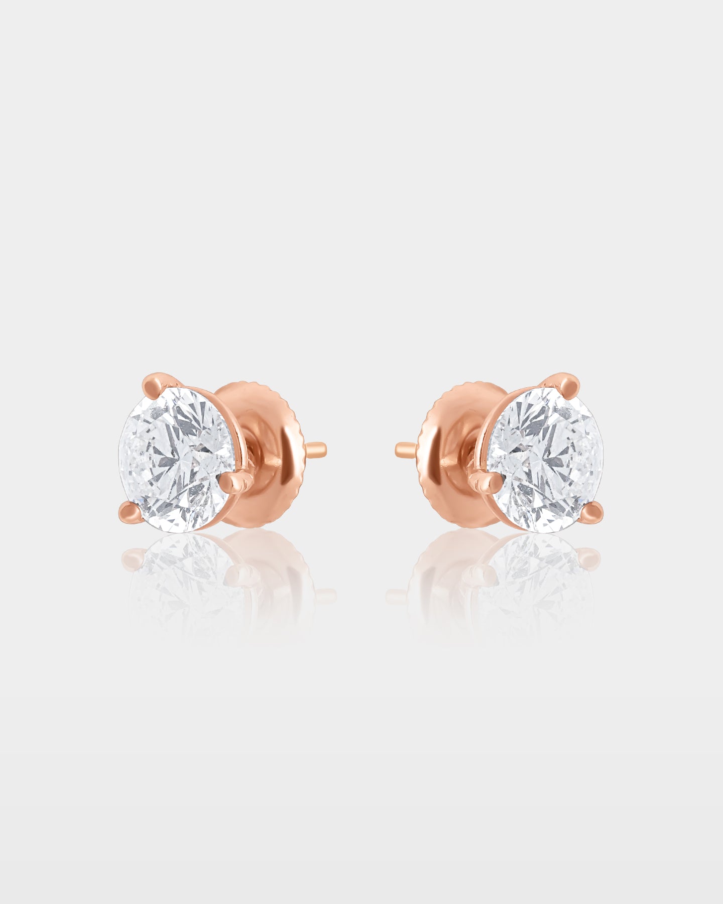 Side and reverse studio view of round diamond martini stud earrings showing the 14k rose gold posts and cone-shaped settings