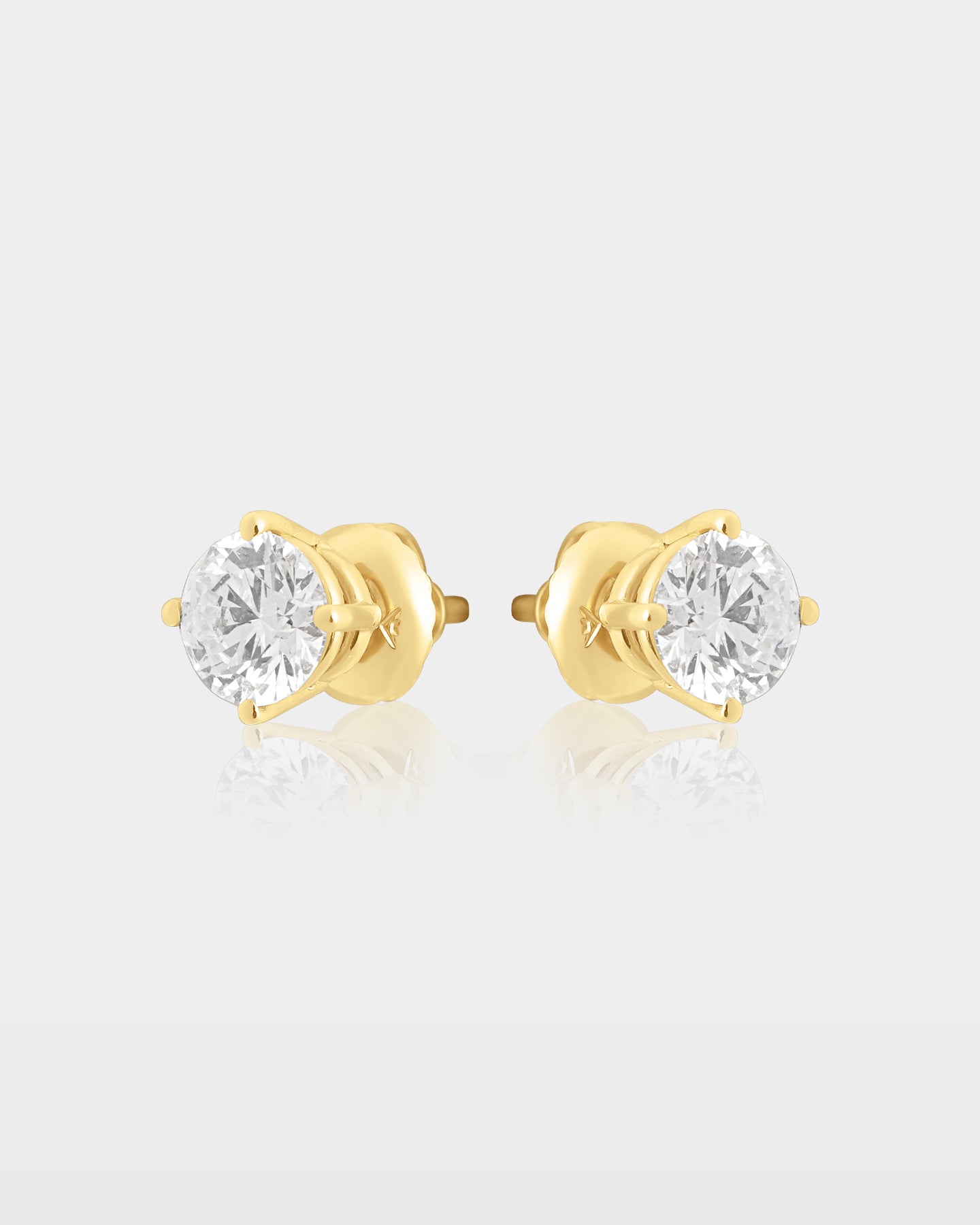 Side and rear studio view of round diamond solitaire stud earrings with yellow gold posts, baskets and secure earring backs